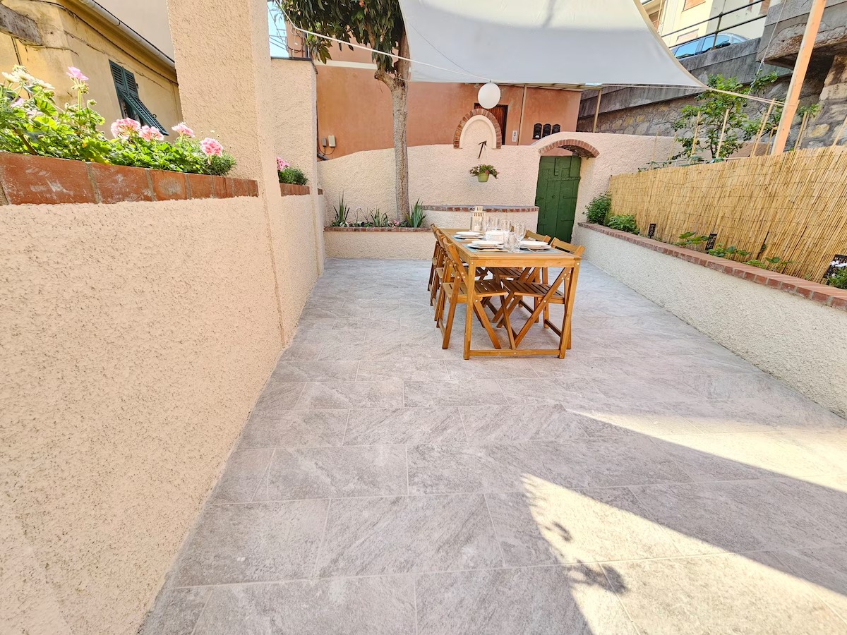 Cortile privato con tavolo da pranzo in legno e vela ombreggiante