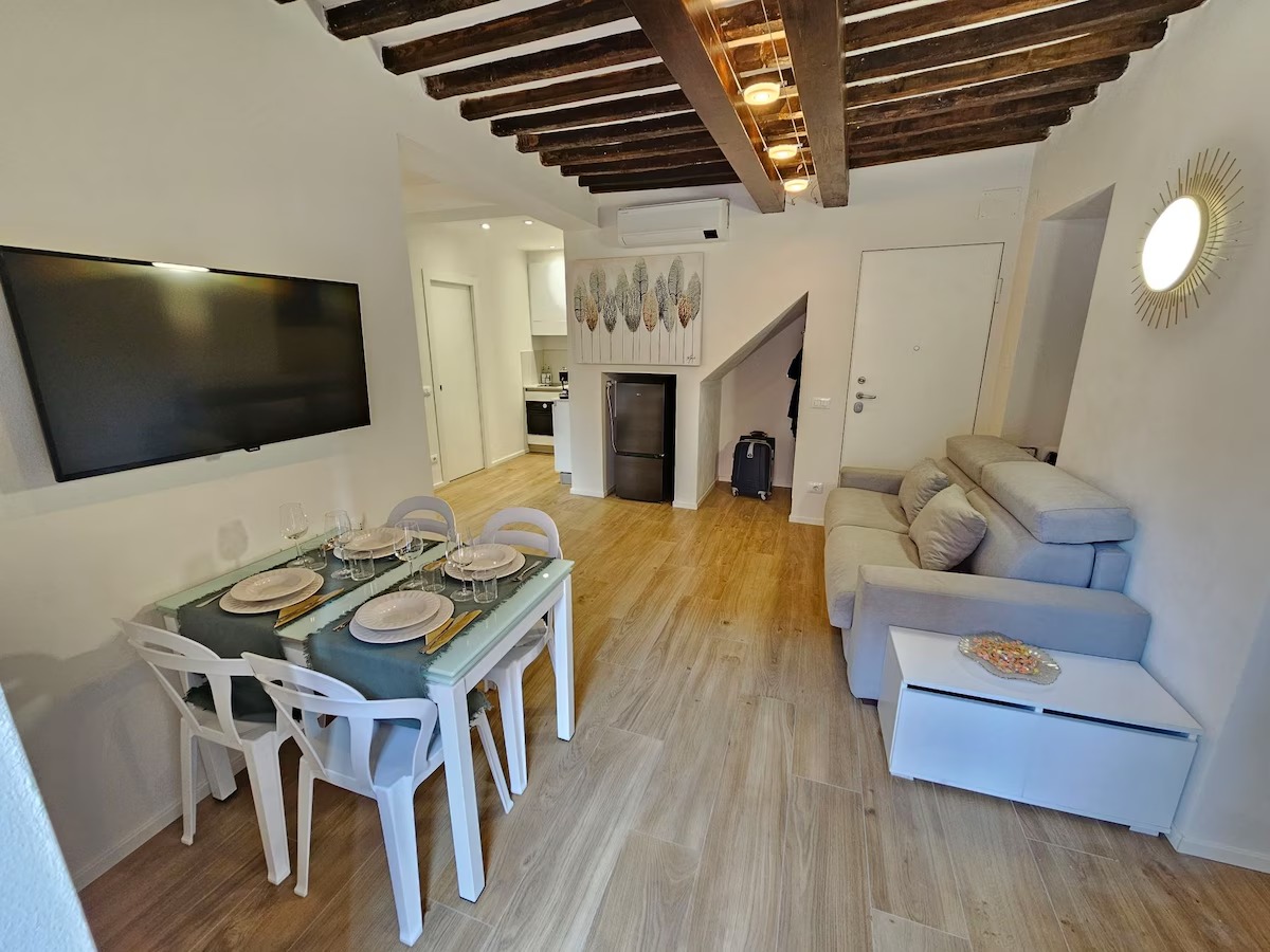 Zona giorno con TV, tavolo da pranzo e cucina sullo sfondo