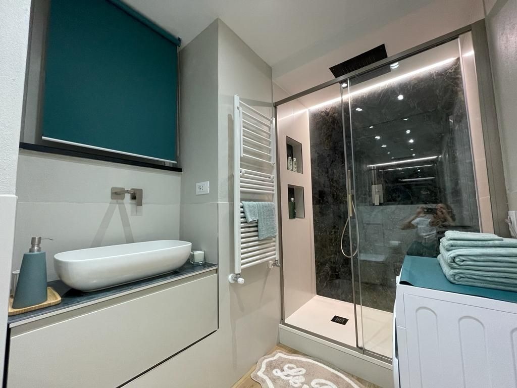 Bagno con doccia, lavabo e lavatrice
