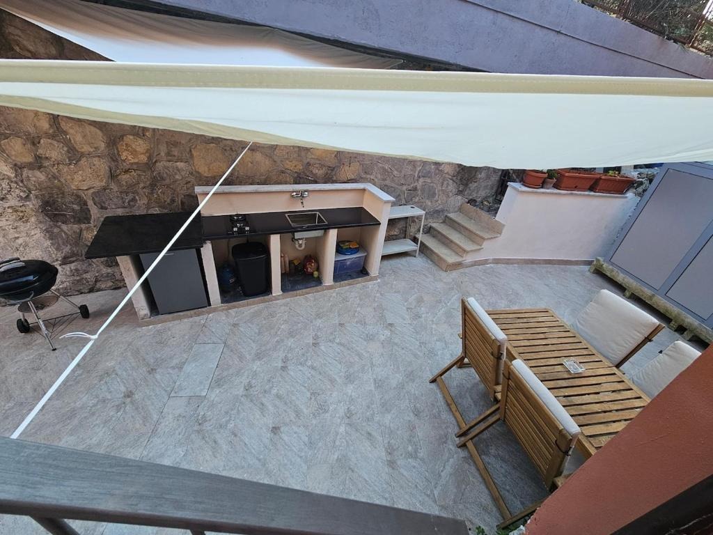 Cortile con vela ombreggiante e cucina esterna